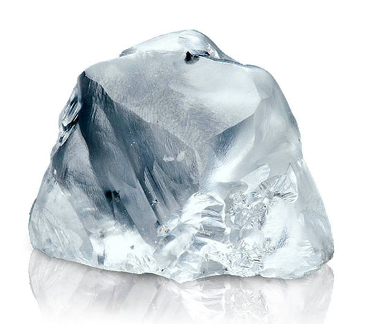 Large rough diamond crystal with sharp edges and clear, translucent appearance, resting on a reflective surface.