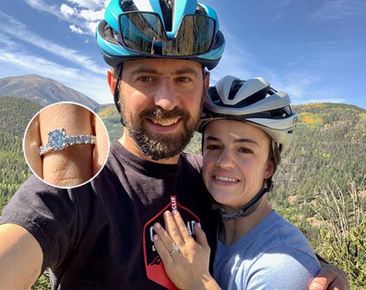 Couple posing outdoors while mountain biking, with the woman showing off her engagement ring in close-up.