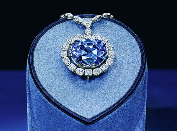 The Hope Diamond, a large blue diamond surrounded by smaller white diamonds, displayed on a velvet stand.