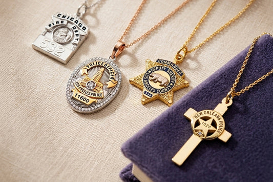 Assorted police and fire department jewelry necklaces, including badge and cross pendants, displayed on a fabric surface.