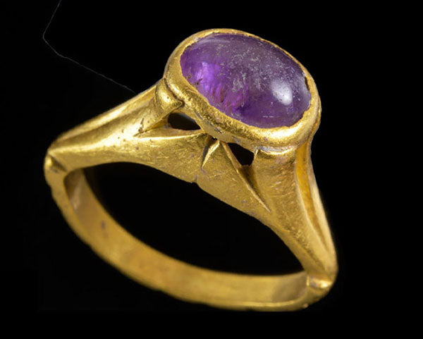 Gold ring featuring a purple amethyst gemstone set in a vintage design, with intricate detailing and a polished finish.
