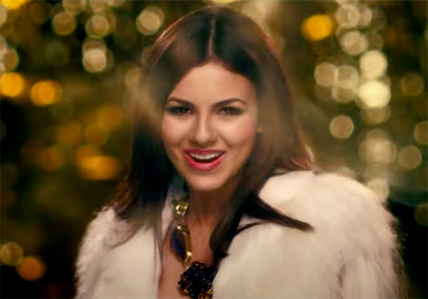 Close-up of a smiling woman in a fur coat with bold jewelry, set against a dreamy, bokeh-lit background, exuding a glamorous and festive vibe.