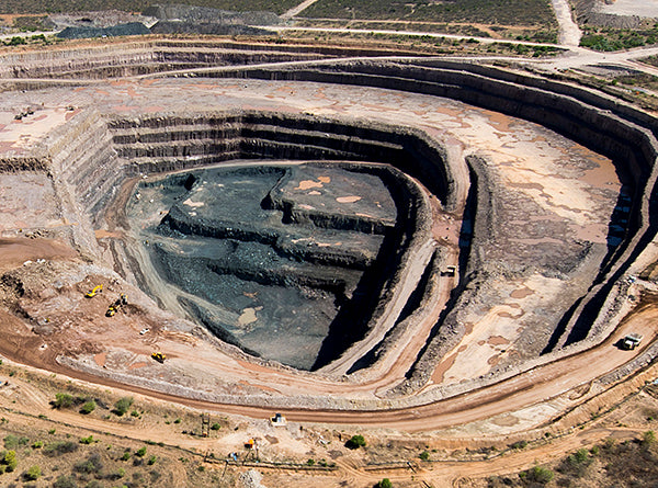 Aerial view of a large open-pit mine showing layers of earth being excavated for mining purposes.