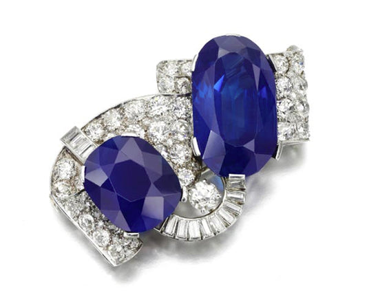 Vintage sapphire and diamond brooch featuring two large oval sapphires and sparkling diamond accents in a classic design.