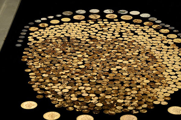 A large collection of various gold and silver coins arranged in a circular pattern on a black surface.