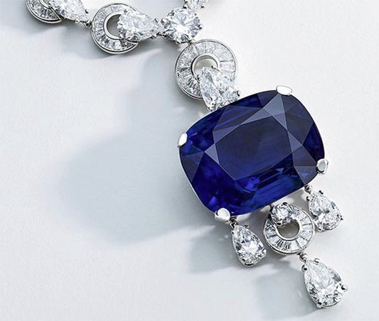 Close-up of a luxurious necklace featuring a large sapphire surrounded by diamonds and pear-shaped diamonds.