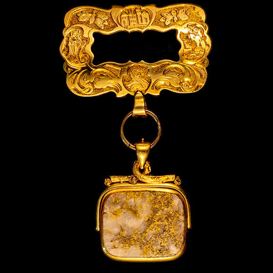 A vintage golden locket with intricate engravings, featuring a square mineral gemstone at its center, showcasing fine craftsmanship and antique design.