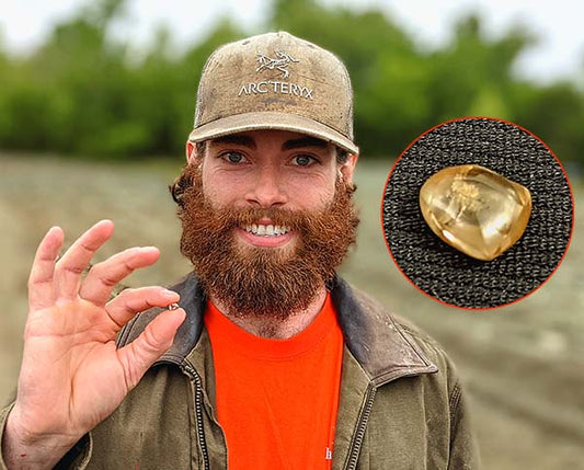 Man with a beard and a cap smiling while holding a gemstone he found, with a close-up of the yellow crystal in an inset photo.