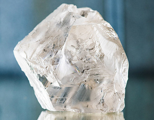 Large, rough diamond crystal with clear, translucent edges reflecting light, showcasing its raw, natural form.
