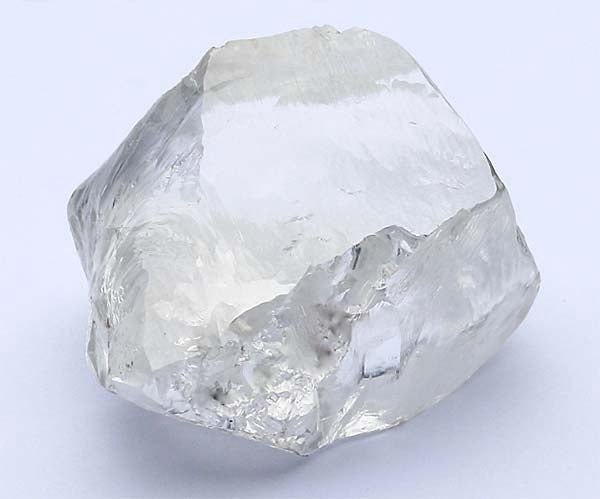 Uncut rough diamond with clear, translucent appearance and natural facets, showcasing its raw form before processing.