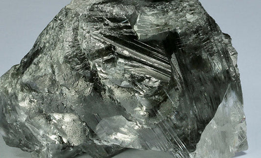 Close-up of a large, rough metallic mineral with shiny, crystalline surface texture, possibly a form of graphite or mica.