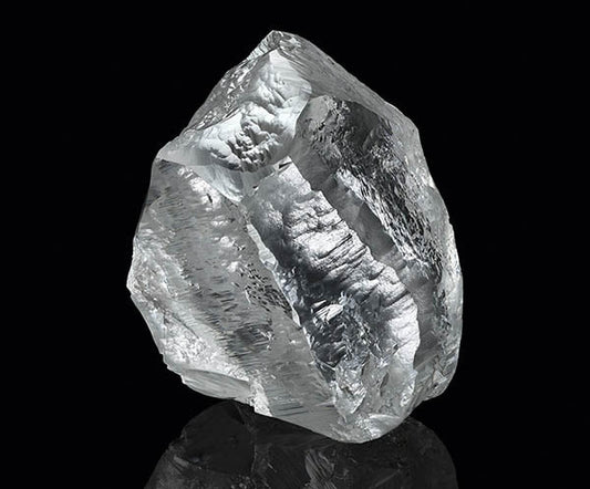 A large, rough diamond crystal with visible facets, reflecting light against a black background.