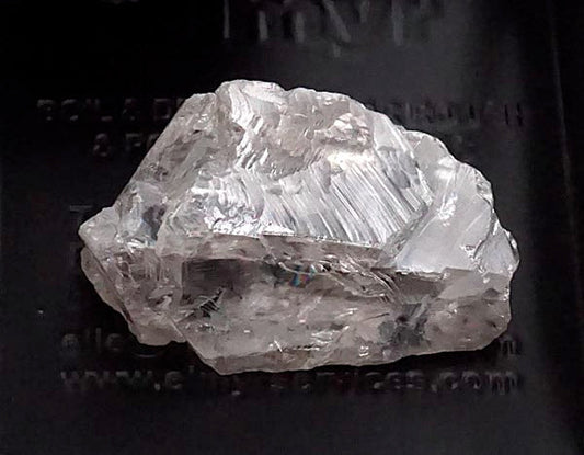 Rough diamond crystal with visible facets, displaying clear, transparent properties and unique texture.