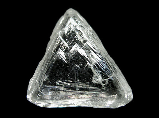 A large, clear triangular-shaped diamond crystal with intricate internal patterns, against a black background.