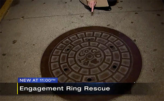 Person pointing at a manhole cover, marking the spot where an engagement ring was rescued.