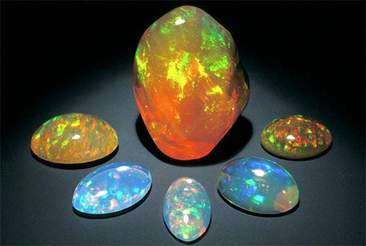A collection of vibrant opal gemstones in various shapes and colors, displaying brilliant rainbow reflections.