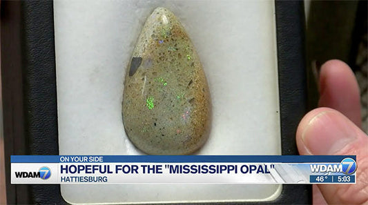 Close-up of the rare 'Mississippi Opal' gemstone with its vibrant iridescent colors, displayed in a box with a news banner from WDAM7 Hattiesburg.