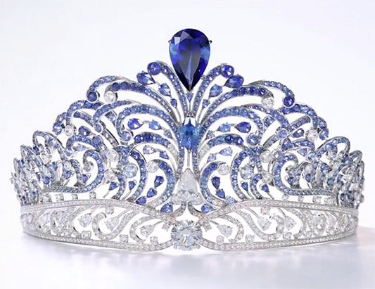 Elegant silver tiara adorned with blue sapphires and diamonds, featuring a large pear-shaped sapphire at the center.