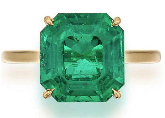 Emerald gemstone ring with a large rectangular cut, set in yellow gold, showcasing vibrant green hues and clear clarity.