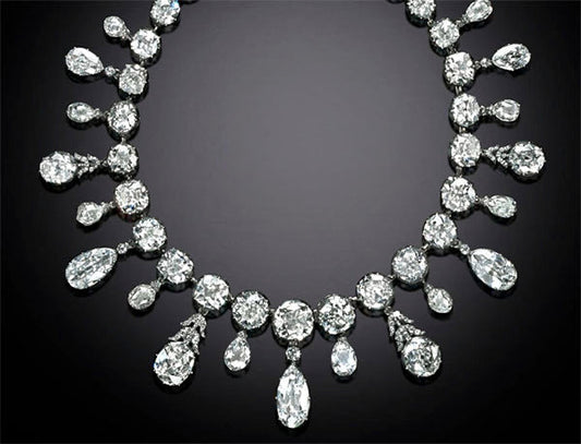Elegant diamond necklace featuring multiple pear-shaped and round diamonds, arranged in a symmetrical pattern with brilliant clarity, set in silver or white gold, showcased against a dark background.