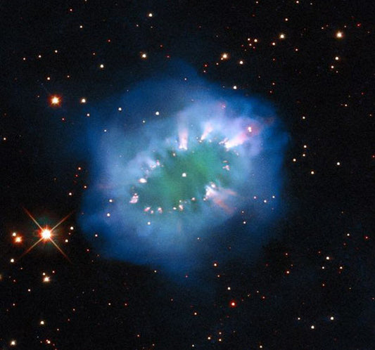 Close-up of a vibrant nebula in space with swirling blue and green gases surrounded by distant stars, captured in high-resolution astronomy image.
