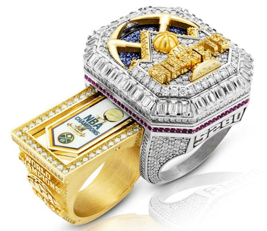 Close-up of a luxurious NBA Championship ring, featuring diamonds, gold accents, and intricate detailing with the Denver Nuggets logo and 'WORLD CHAMPION' inscription.