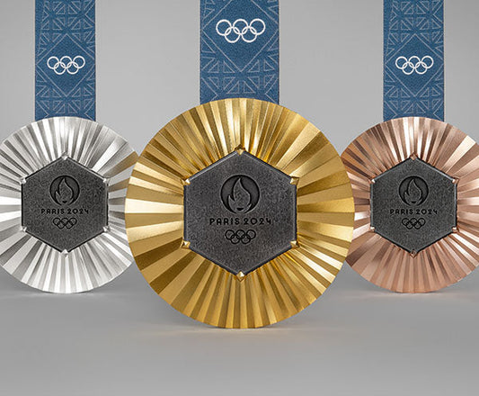 2024 Paris Olympic gold, silver, and bronze medals with a unique sunburst design and blue Olympic ribbons.