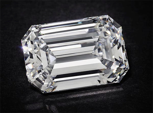 Large, clear, emerald-cut diamond with sharp facets, showcasing brilliance and clarity against a dark background.