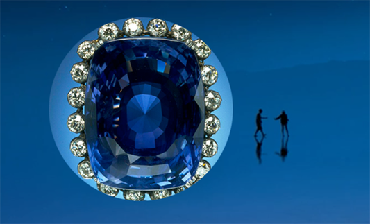 Sapphire ring surrounded by diamonds with a silhouette of a couple walking in the background, set against a blue sky.