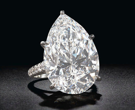 Large pear-shaped diamond ring with a sparkling white diamond, set in a platinum band with smaller diamonds on the band.