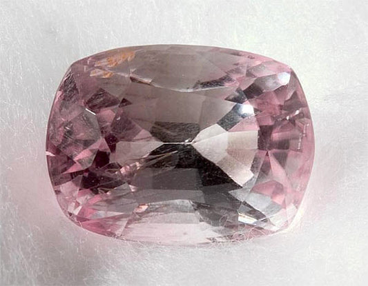 Close-up of a pale pink cushion-cut sapphire gemstone, showcasing its clarity and vibrant color.
