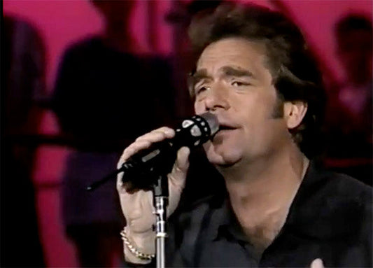 Male singer performing live on stage holding a microphone.