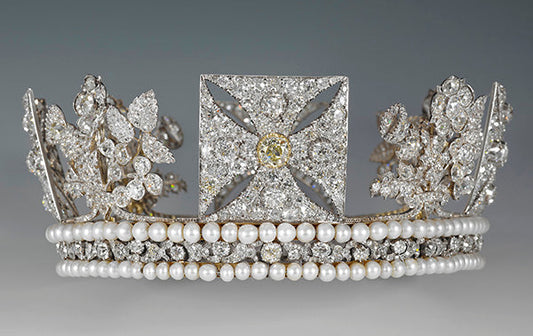 Close-up of an elegant diamond tiara with pearl bands, featuring intricate floral designs and a yellow diamond centerpiece, set against a neutral background.