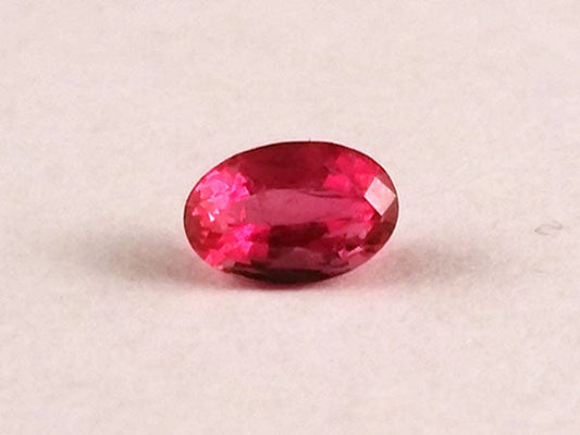 Close-up of an oval-shaped pink sapphire gemstone with a faceted surface, highlighting its vibrant color and clarity.