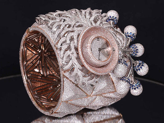 Close-up of an intricate diamond-encrusted luxury watch bracelet with a rose gold bezel and blue gemstones.