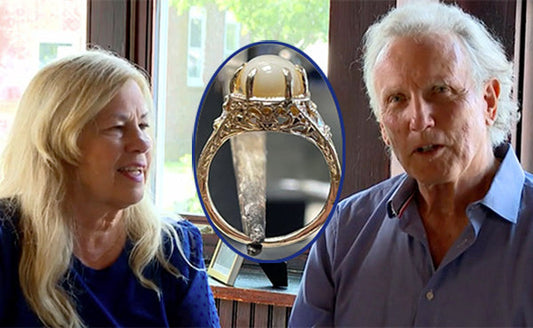 Couple sitting together with a close-up of a vintage engagement ring featuring a pearl and intricate design, symbolizing a romantic story.