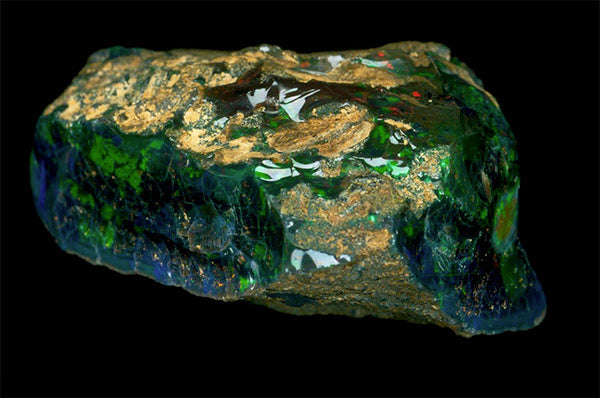 Close-up of a raw green opal stone with a shiny surface and colorful reflections, showcasing the natural beauty and intricate patterns of the gemstone.