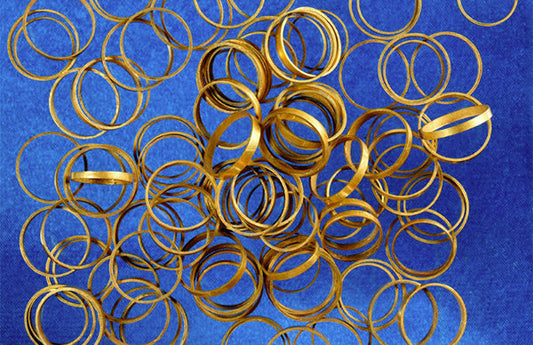 Collection of thin ancient gold rings displayed on a blue fabric background, showcasing archaeological gold jewelry artifacts.