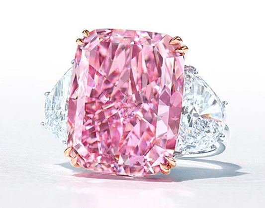 Close-up of a luxury pink diamond ring featuring a large pink cushion-cut diamond center stone with two white diamonds on each side.