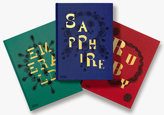 Three hardcover books with titles 'Emerald', 'Sapphire', and 'Ruby' on colorful backgrounds in green, blue, and red with gold text.