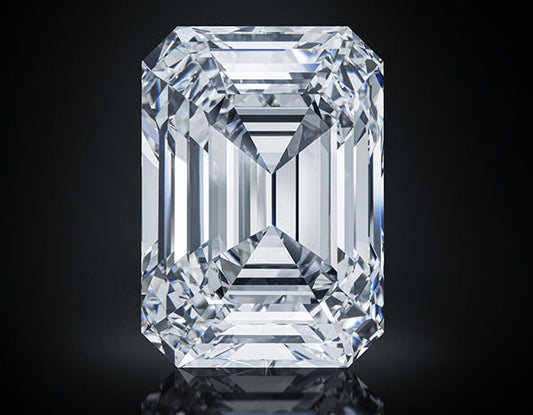 Large, clear emerald-cut diamond with multiple facets, reflecting light against a dark background.