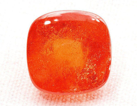 Close-up of a polished orange gemstone, showcasing its smooth surface and vibrant color.