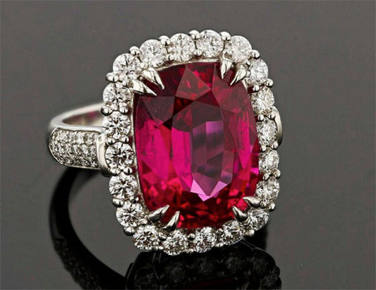 Luxury ruby and diamond ring with a large oval ruby surrounded by a halo of round diamonds on a white gold band.