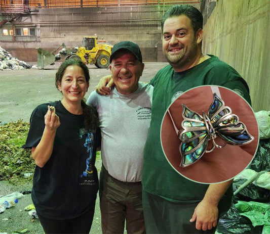 Group of people smiling and posing at a waste facility after finding a butterfly-shaped silver ring with abalone shell inlay.