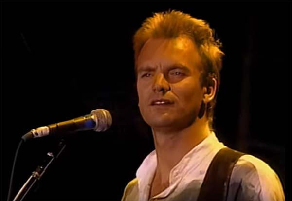 Sting performing live on stage with his guitar, showing a focused expression during a concert.