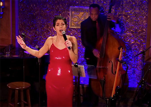 Female singer performing on stage in a red dress with a jazz bassist playing in the background.