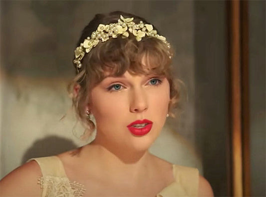 Close-up of Taylor Swift wearing a floral headband, with red lipstick and a soft, elegant look.