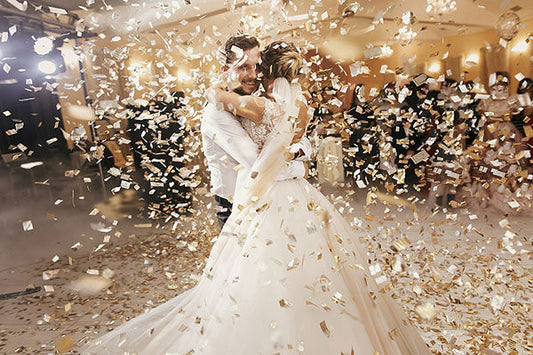 Couple enjoying their first dance as husband and wife, surrounded by gold confetti in a romantic wedding celebration.