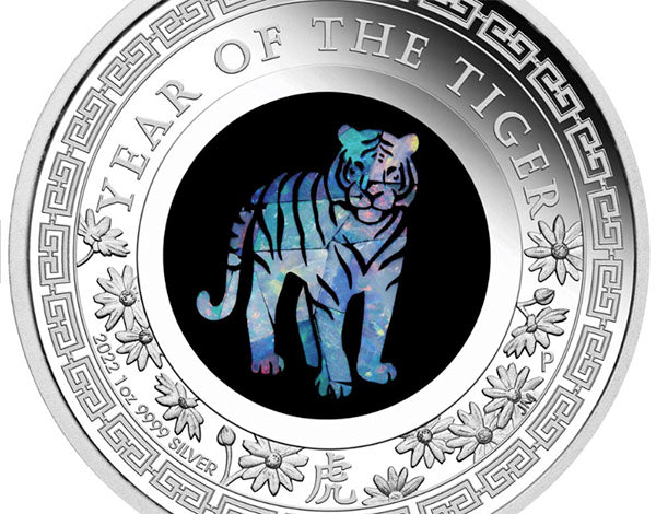Close-up of a silver coin commemorating the 'Year of the Tiger,' featuring a colorful tiger design in the center, surrounded by floral patterns and the inscription '2022 1 oz 9999 Silver.