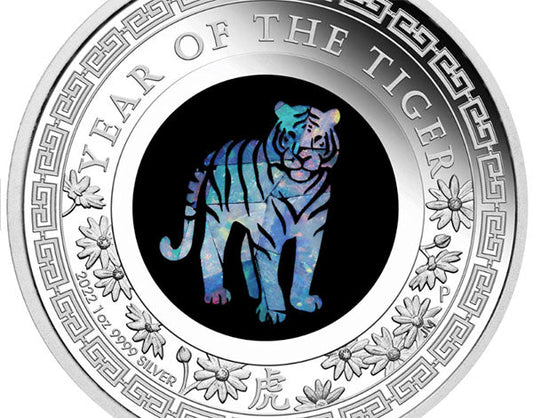 Close-up of a silver coin commemorating the 'Year of the Tiger,' featuring a colorful tiger design in the center, surrounded by floral patterns and the inscription '2022 1 oz 9999 Silver.